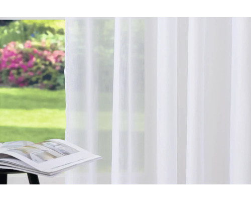Voilage blanc devant une fenêtre avec vue sur le jardin