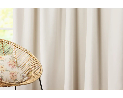 Rideau et fauteuil en rotin avec coussin devant une fenêtre