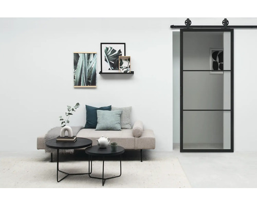 Wohnzimmer mit Sofa, Couchtischen, Wandbildern und Schiebetür