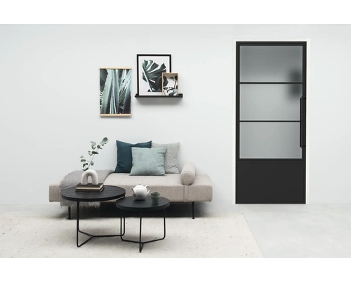 Wohnzimmer mit Sofa, Couchtischen und einer Tür mit Glaseinsatz