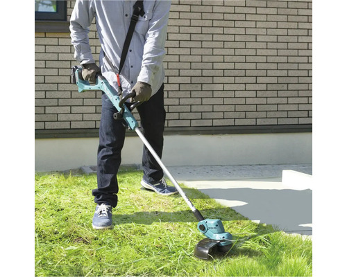 Mann bedient einen Akku-Rasentrimmer im Garten.