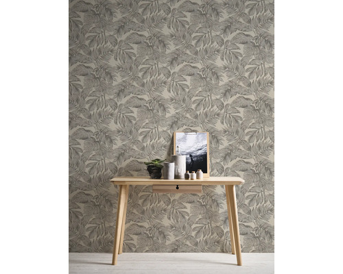 Raumansicht mit Blattmuster-Tapete, Holztisch, Pflanze, Dekoration und gerahmtem Bild