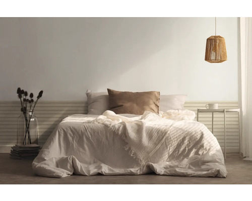 Schlafzimmer mit Bett, Kissen, Tagesdecke, Nachttisch und Lampe