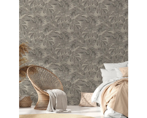 Ein Schlafzimmer mit einer Wandtapete mit Blattmuster, einem Rattansessel und einem Bett.