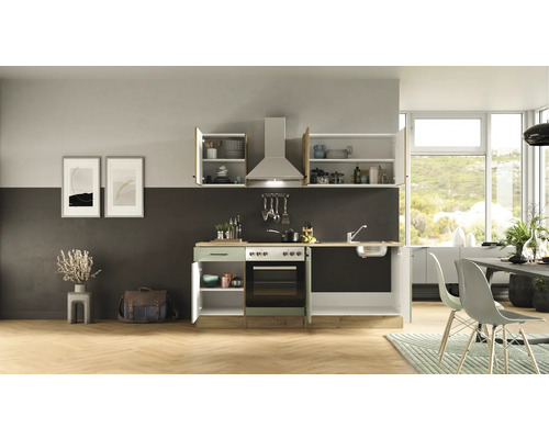 Küche mit Spüle, Herd, Dunstabzugshaube und Hängeschränken in einem hellen Raum.