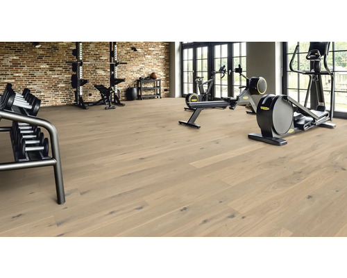 Fitnessraum mit Hantelregal, Trainingsgeräten und hellem Holzboden