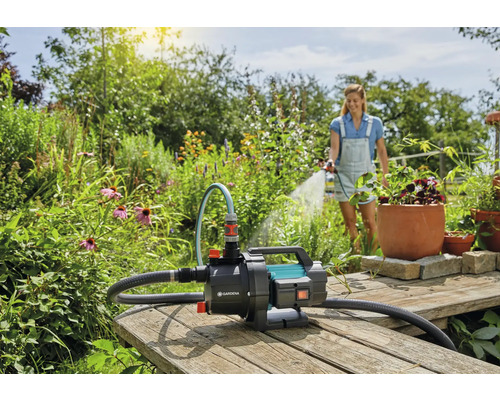 Gartenszene mit einer Frau, die mit einer Gardena Gartenpumpe ihren Garten bewässert.