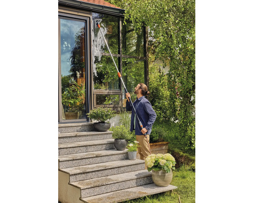 Un homme nettoie les fenêtres avec un lave-vitre télescopique sur une véranda