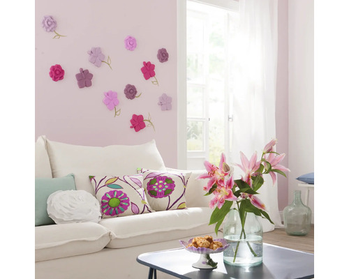 Salon avec canapé blanc, coussins décoratifs et décoration murale avec motifs floraux