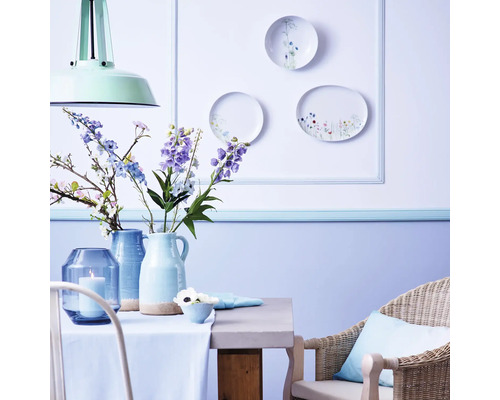 Helles Esszimmer mit Tisch, Stuhl, Vasen und dekorativen Tellern an der Wand