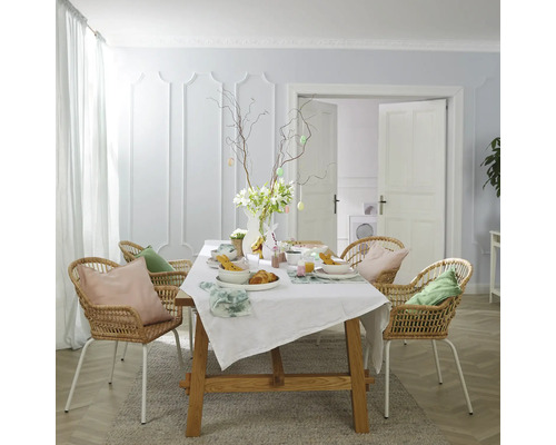 Festlich gedeckter Esstisch mit Rattanstühlen in hellem Raum.