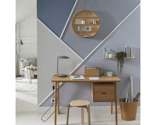 Arbeitszimmer mit Schreibtisch, Stuhl, Regalen und geometrischer Wandgestaltung