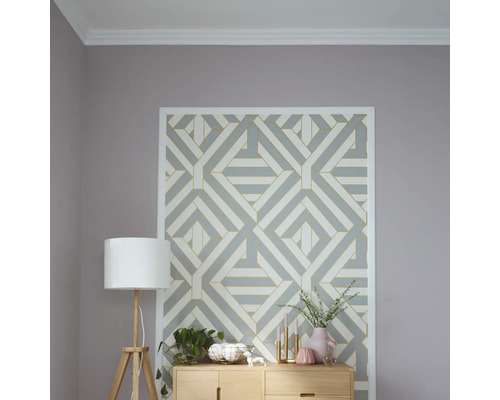 Dekoratives Zimmer mit geometrischer Mustertapete, Stehlampe und Holzkommode