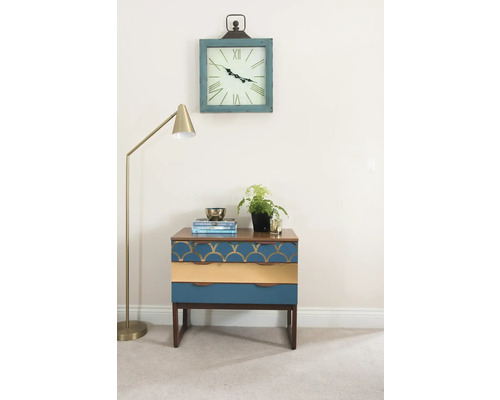 Scène décorative avec une table de chevet à trois tiroirs, un lampadaire et une horloge murale.