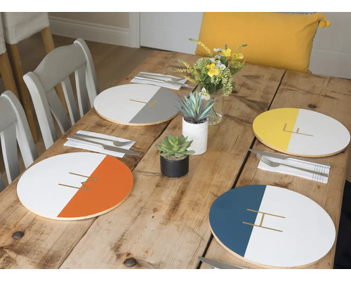 Table à manger avec des sets de table de différentes couleurs, de la vaisselle et de la décoration
