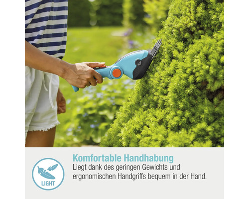 Frau schneidet mit einer Akku-Grasschere eine Hecke