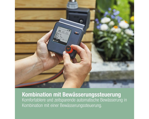 GARDENA Bewässerungssteuerung in der Hand vor einer Holzwand
