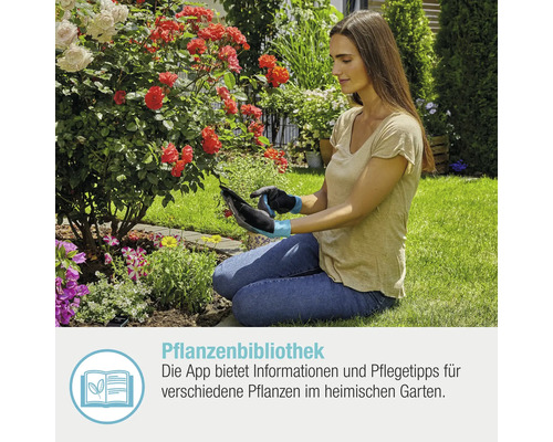Frau benutzt Tablet im Garten mit Pflanzenbibliothek App