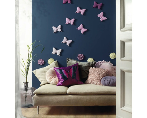 Dekoratives Wohnzimmer mit Sofa, Kissen, Wanddekoration in Schmetterlingsform und Blumenvase