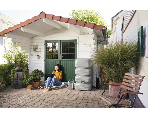 Vue de jardin avec citerne, femme avec tablette et cabanon de jardin