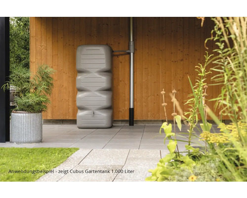 Scène de jardin avec un réservoir d''eau de pluie Cubus gris de 1000 litres contre un mur en bois