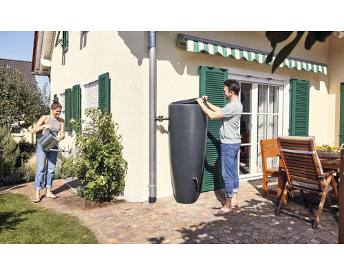 Des personnes utilisent un récupérateur d''eau de pluie pour arroser le jardin dans un jardin ensoleillé.