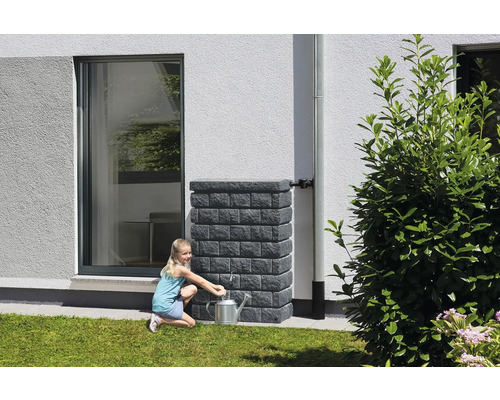 Fille remplissant un arrosoir au réservoir d''eau de pluie