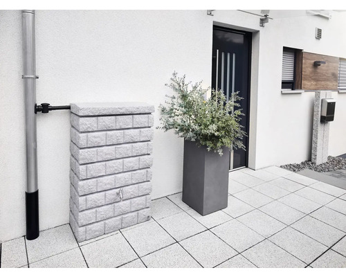 Réservoir d''eau aspect pierre à côté d''une descente pluviale et d''un bac à plantes devant une maison