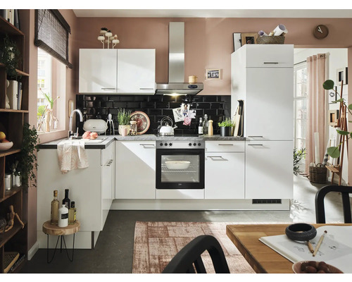 Cuisine claire avec armoires blanches, évier et appareils électriques devant une crédence en carrelage noir