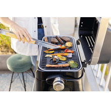 Une personne grille des légumes et de la viande sur un barbecue.