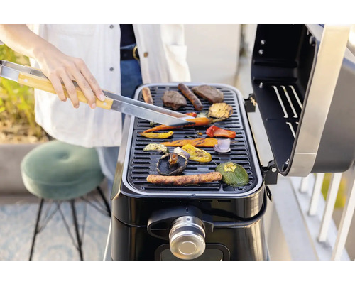 Une personne grille des légumes et de la viande sur un barbecue.