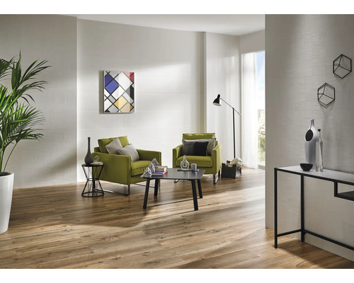 Salon lumineux avec deux fauteuils, une table basse, un lampadaire, un buffet et un plancher en bois