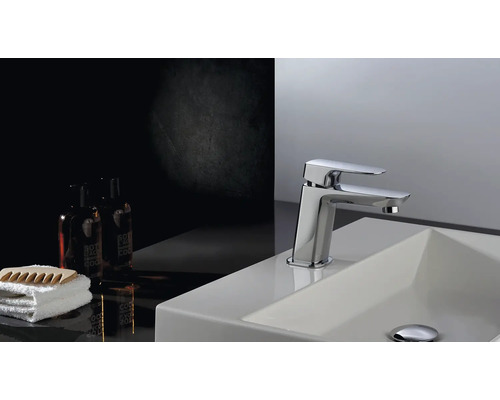 Waschtischarmatur auf einem Waschbecken mit Handtuch und Kosmetikprodukten