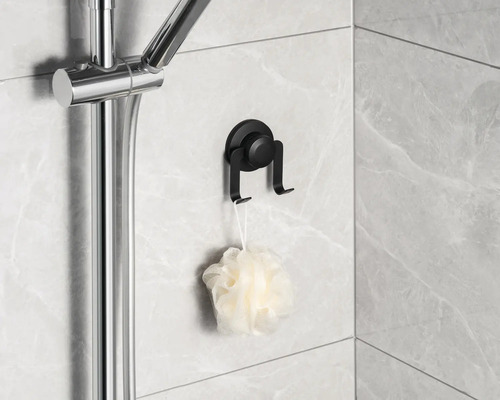 Schwarzer Saugnapf Haken mit Duschschwamm an gefliester Wand neben Duschstange