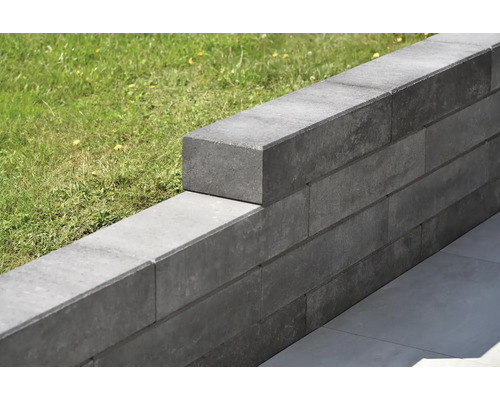 Un mur de jardin gris en blocs de béton borde une pelouse.