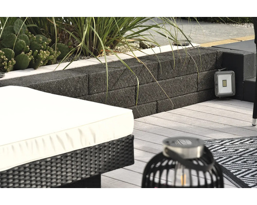 Scène de terrasse avec mur en blocs de béton, projecteur LED, mobilier de salon et lanterne décorative