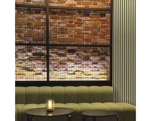 Intérieur avec canapé, tables et mur en briques décoratif derrière un grillage métallique