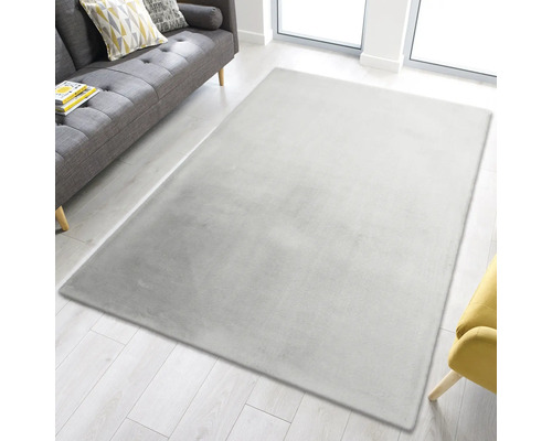 Tapis rectangulaire en fibre synthétique dans un salon avec canapé et fenêtre
