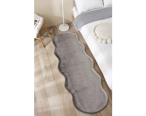 Photo d''intérieur d''une chambre avec un lit et un tapis gris aspect fourrure.