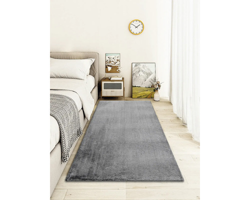 Tapis gris dans une chambre avec lit et table de chevet
