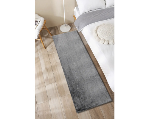 Tapis de couloir gris dans une chambre sur un parquet à côté d''un lit.