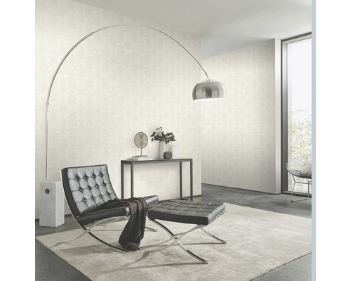 Salon avec papier peint, fauteuil, tabouret et lampadaire.