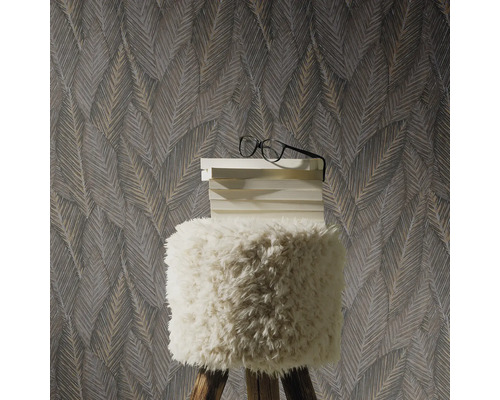 Dekorative Tapete mit Blättermuster hinter einem Hocker mit Bücherstapel und Brille