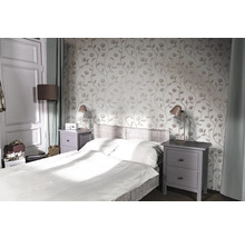 Schlafzimmer mit Bett, Nachttischen und floraler Tapete