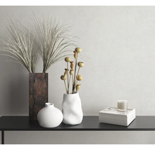 Nature morte décorative avec vases, herbes ornementales, branches décoratives et bougie sur une console