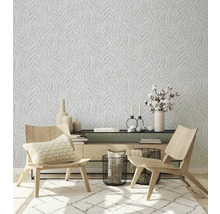 Salon avec papier peint à motifs, tapis et meubles en bois.