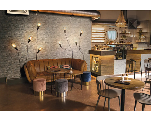 Intérieur d''un café avec canapé, tables, tabourets et appliques murales devant un mur de briques