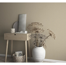 Arrangement décoratif avec table d''appoint, vase avec fleurs séchées et éléments décoratifs devant un mur uni.