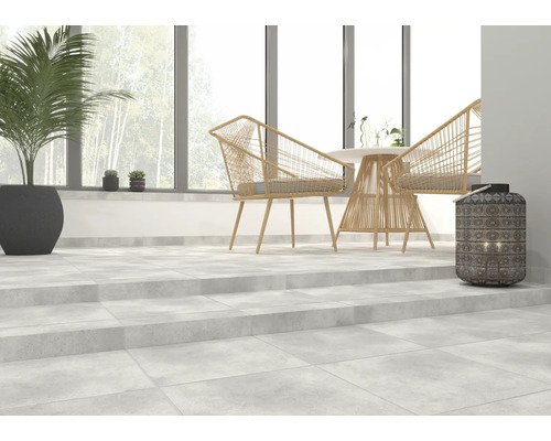 Heller Raum mit Betonfliesen, Rattansesseln, Tisch und Dekoration