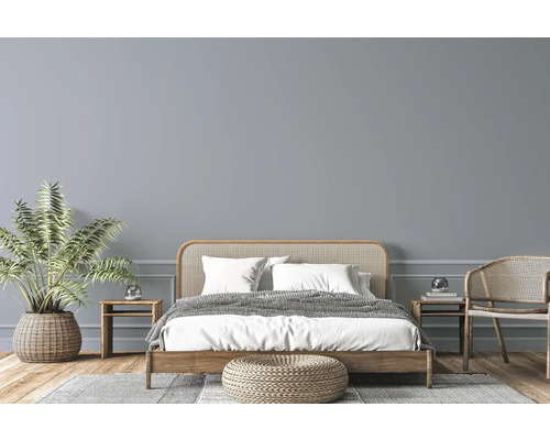 Helles Schlafzimmer mit Holzbett, Korbmöbeln, Zimmerpflanze und Teppich